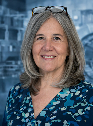 Bild: Das Bild zeigt Backoffice-Managerin Andrea Roszyk. Sie ist etwa Mitte Fünfzig, trägt eine grüne Bluse und hat graue Haare.