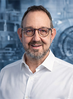 Bild: Das Bild zeigt Firmengründer Michael Roszyk. Michael ist ein Mann ca. Mitte fünfzig, mit Brille, Bart, grauen Haaren und einem freundlich lächelnden Gesicht.