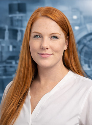 Bild: Das Bild zeigt Marketing-Managerin Vanessa Probst. Sie ist eine junge Frau mit langen, roten Haaren und trägt ein weißes Hemd.