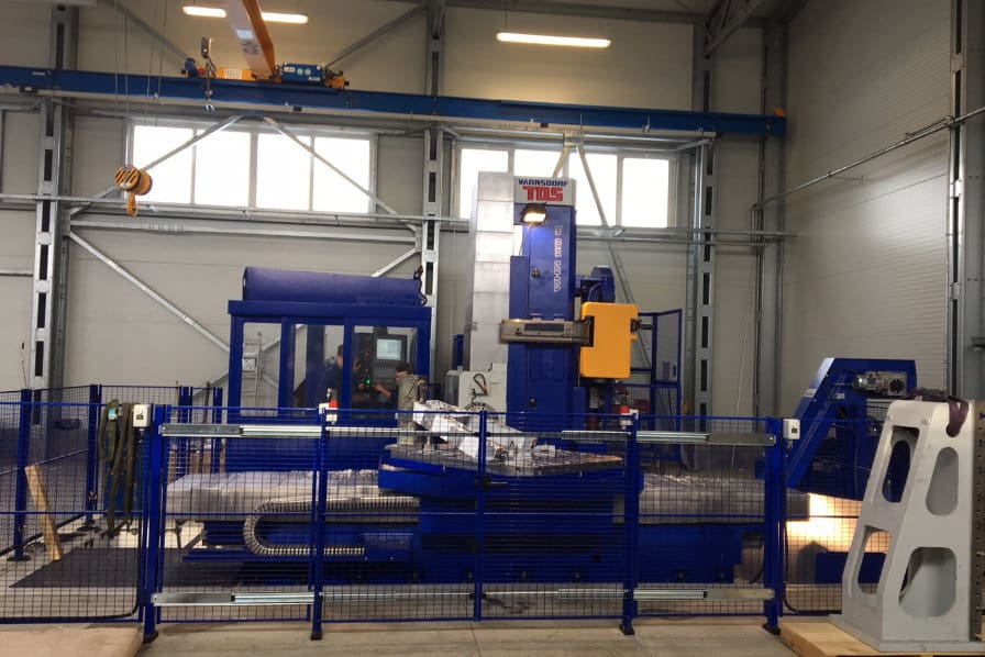 Blaues Bohrwerk mit Rundtisch und Schutzumhausung in einer Fertigungshalle